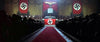 A large hall adorned with Nazi flags and symbols, crowds facing a stage where a speaker stands—an iconic World War II scene featured in the “Battle of Britain (1969)” DVD.