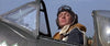 A pilot in vintage gear sits in the cockpit, gazing upward with determination against a blue sky—capturing the epic spirit of World War II as seen in Battle of Britain (1969) DVD.