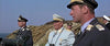 A group of military officers stands on a rocky coast under a clear sky, evoking WWII camaraderie as seen in the "Battle of Britain (1969) DVD," with two in dark uniforms and one smiling officer in a light uniform at the center.