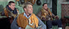 Three men in flight jackets and life vests sit with helmets and gear in a military briefing room, one holding a newspaper—a scene reminiscent of the intense action depicted in the Battle of Britain (1969) DVD.