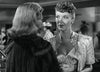 Two women converse in a formal black and white scene—one in an embroidered dress, the other in a dark fur coat. Experience timeless 1940s Hollywood elegance with Caught (1949) DVD, perfect for classic movie collectors.