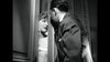 A woman anxiously peers through a door at a man in a suit in this evocative black-and-white scene from "Caught (1949)"—a rare, hard-to-find classic now available on DVD.