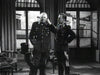 Two men in military uniforms stand in a formal, historic room. One speaks on the phone while the other stands beside him—a classic moment from The Tanks Are Coming (1951) DVD, perfect for fans of vintage war films.