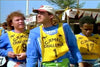 Three men in yellow Camel Challenge bibs—numbers 19, 1, and 17—over blue shirts stand outdoors, focused and ready for an event. A tent and trees in the background evoke a scene from the rare Crossing the Line (1990) DVD.