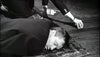 A man lies face down on a rug with his eyes closed, while another’s hand reaches nearby, creating suspense like that found in the classic Murder Ahoy (1964) DVD. The scene is tense and dramatic.