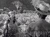 A Native American man in feathers speaks to a man in a fringed jacket and wide-brimmed hat amid desert rock formations, recalling classic black-and-white scenes like those found in The Yellow Tomahawk (1954) DVD.