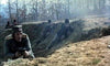 A group of soldiers in historical uniforms take cover in a dirt trench, aiming their rifles as bare trees loom behind—a scene reminiscent of the film "Massacre at Noon (1975)" now available on DVD.