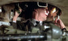 A man in military uniform sits inside a cramped tank turret, peering through a viewing device with one hand on the controls—evoking the tense war scenes depicted in Wheels of Terror (1987) DVD.
