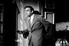 A suspenseful black and white scene from "Son of Dracula (1943) DVD" shows a man in a suit, partially hidden behind a wall, cautiously holding a revolver—evoking classic horror film moments.