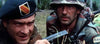 Two soldiers in camouflage crouch in tall grass—one with a pistol and black beret, the other helmeted—both gaze ahead, recalling scenes from rare movies like Tornado: The Last Blood (1983) DVD.
