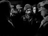 A group of men in heavy clothing and hats stand together in low light, their serious expressions evoking the tense atmosphere of a classic war drama like "Time Limit (1957)" now available on DVD.