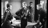Five men in military uniforms engage in a tense discussion, capturing classic World War II drama. "The One That Got Away (1957) DVD" is perfect for fans seeking rare war movies on DVD.