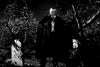 A man in a dark cape stands among gravestones under moonlight in the classic black-and-white film "Son of Dracula (1943)," creating a spooky, unforgettable horror movie atmosphere with eerie tree shadows and a haunting graveyard scene.