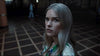 A woman with long, straight blonde hair and a serious look stands indoors on a checkered floor in a dimly lit setting, capturing the eerie vibe of "Haunting of Queen Mary (2023)" DVD.