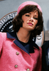A woman with brown hair styled in a bob stands in front of a seal resembling the presidential seal, dressed in a pink suit and matching hat adorned with pearls—an image reminiscent of the Jacqueline Bouvier Kennedy DVD (1981) cover.