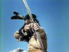 A person in traditional Native American attire draws a bow under a blue sky, embodying the spirit of rare westerns like "Kentucky Rifle (1955)"—now available on DVD.