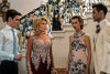 Four people in formal wear stand before a decorated staircase, looking tense—like suspects from Murder at the Mansion (2018) DVD. Flowers and garlands suggest a special event in this rare movie’s ornate setting.