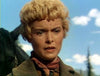 A person stands outdoors in classic western DVD style, wearing a brown jacket and red neckerchief, with trees, sky, and a black horse behind them. Product shown: The Naked Spur (1953) DVD.