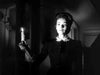 A woman in old-fashioned clothing holds a lit candle in a shadowy room, her face illuminated by its soft glow, evoking the dramatic, mysterious atmosphere of “The Ghost and Mrs. Muir (1947)” on DVD.