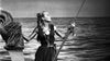A woman on a boat in calm seas holds a rope and a serpent's head—a striking black-and-white scene echoing classic Viking adventure, as seen in "Saga of the Viking Women (1957)" DVD.
