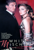 A man in a tuxedo and a woman in a silver gown stand together against a red background. Text reads: White Mischief DVD (1987). In the dazzling world of British expatriates—where wife swapping, drugs, and chocolate covered lobsters were commonplace—murder seemed shockingly out of place. Experience this unforgettable true crime drama on the White Mischief DVD (1987).