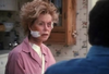 A woman with a bandage on her cheek, dressed in a pink shirt, sits indoors wearing a concerned expression as she faces someone whose back is turned to the camera, evoking the suspenseful atmosphere of classic films like *With Murder in Mind (1992) DVD*.
