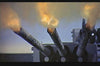 Three large naval gun barrels fire with bright flames and smoke against a gray-blue sky—a powerful scene reminiscent of World War II naval battles, as seen in Pursuit of Graf Spee (1956) DVD.