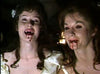 Two women in white dresses, blood on their lips and sly smiles, evoke classic gothic horror—like a scene from Count Dracula (1977) DVD. The eerie lighting adds to the suspenseful atmosphere, reminiscent of timeless vampire tales.