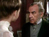 An older man with gray hair and a dark suit gazes intensely at a young woman in a light blouse—a moment evoking gothic horror classics like the Count Dracula (1977) DVD.