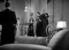 Five people in formal evening attire converse in an elegant, chandelier-lit room with luxurious furniture on the cover of the Dracula’s Daughter (1939) DVD. Three women stand together while two men are nearby, all captured in a classic, vintage black-and-white style reminiscent of a classic horror movie.