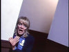 A blonde-haired woman appears terrified, gripping a wall in a shadowy room. Her wide eyes and open mouth convey shock or fear—perfectly reflecting the suspenseful mood of Maniac Cop, the 1988 cult horror film now available for collectors on DVD as Maniac Cop DVD (1988).