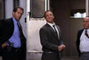 Three men in suits stand outside a building. The smiling, handcuffed man in the center resembles a scene from Find Me Guilty (2006) DVD, a true crime courtroom drama available on DVD.