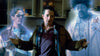 A man stands in a kitchen with two spectral, translucent figures—one wearing glasses and a sweater, the other clad in a denim jacket—glowing faintly on either side of him, as if they’ve materialized straight from “The Frighteners (1996)” DVD.