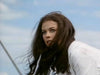 A woman with long dark hair and a serious expression looks to the side in a white outfit against a blue sky—evoking the spirit of a Native American frontier adventure from Grayeagle (1977) DVD.