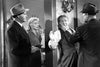 Three people confront a man against a wall: one grabs his face, another points a gun, and a woman watches—all dressed in 1940s-style clothing in a tense black-and-white scene that captures the suspense and intrigue of classic noir crime thrillers, like the rare hard-to-find film Kiss Tomorrow Goodbye (1950), now available on DVD.