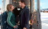 A woman with a backpack and a man stand facing each other by an open van decorated with lights, evoking the warmth of a family Christmas movie—just like in “Holiday Road Trip (2013),” now available on DVD. Snow blankets the ground outside, and the cozy van interior is visible.