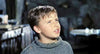 A young boy with short brown hair and a gray sweater looks upward with a puzzled or concerned expression, set against the dimly lit interior of a rustic room—capturing the classic atmosphere beloved by fans and collectors of rare monster movies like Gorgo (1961) DVD.