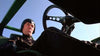 A person in a black helmet and suit sits in a green vehicle, viewed from a low angle with the steering wheel and clear blue sky visible above—capturing the iconic style of Death Race 2000 (1975) DVD.