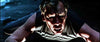 A man in a sleeveless shirt lies on the ground in dramatic lighting, looking up with a tense, intense expression on his face—evoking the gritty atmosphere of a neo-noir thriller like *Point Blank (1967)*, now available on DVD.