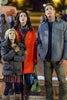 A young girl, a woman in a red coat, and a man in a gray jacket stand together outdoors at night, all gazing upward with wonder—as if they’ve stepped straight out of the heartwarming scenes found in the Magic Stocking (2015) DVD.