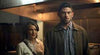 A woman and a man stand indoors under warm lighting, looking serious—echoing the solemn themes of life after death explored in We Go On (2016) DVD, a must-see for collectors of rare films on DVD.
