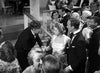 A crowded ballroom scene with elegantly dressed men and women, some shaking hands and others talking, in black and white—a timeless moment reminiscent of classic films like “Dodsworth (1936)” on DVD.