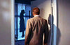 A man in a suit stands in a doorway, gazing at a shadowy figure hanging by the neck in the adjacent room, their silhouette dramatically cast on the wall—a haunting image evocative of classic Hollywood mysteries, as seen in rare hard to find movies like *Black Widow (1954)* DVD.