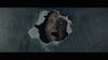 A terrified, pale face with wide eyes and an open mouth peers through a jagged hole in a shadowy wall—reminiscent of chilling moments from the Post Mortem (2020) DVD.