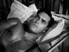 A young man with dark hair lies shirtless on a bed, looking thoughtful—reminiscent of classic films like "Sailor of the King (1953)" on DVD. The black-and-white style evokes timeless drama and introspection.