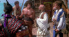A muscular man in a loincloth stands on a ship’s deck with four men in colorful costumes, evoking the 80s fantasy adventure "Sinbad of the 7 Seas (1989)"—now available on DVD—with the ocean in the background.