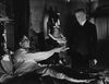 A man reaches for another in a dark, ornate room with an Anubis statue in this suspenseful scene from The Ghoul (1933) DVD, capturing the drama and style of vintage black-and-white horror films and rare classics.