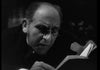 A man with glasses and a serious expression reads a book intently in low light, capturing the suspenseful mood of vintage horror as seen in The Ghoul (1933) DVD.