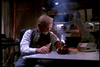 An older man in a vest sits at a desk, welding or working with a sparking tool amid technical equipment in a dimly lit room—a scene reminiscent of classic cyborg action movies like *Eliminators* (1986), now available on DVD.