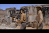 Three men in cowboy hats and Western attire stand outside a rundown desert building; one holds a rifle while another crouches behind a stone wall, all appear alert and tense—capturing the gritty spirit of classic westerns found in Rio Conchos DVD (1964), perfect for fans seeking rare movies on DVD or expanding their classic western DVD collection.